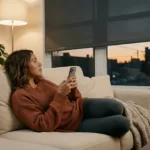 Fotografía de una mujer manipulando el control de sus cortinas con su celular en su casa inteligente