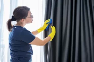 Fotografía de una mujer que sabe cómo lavar cortinas de blackout limpiando con delicadeza las cortinas