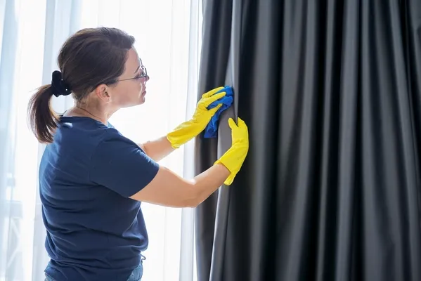 Fotografía de una mujer que sabe cómo lavar cortinas de blackout limpiando con delicadeza las cortinas