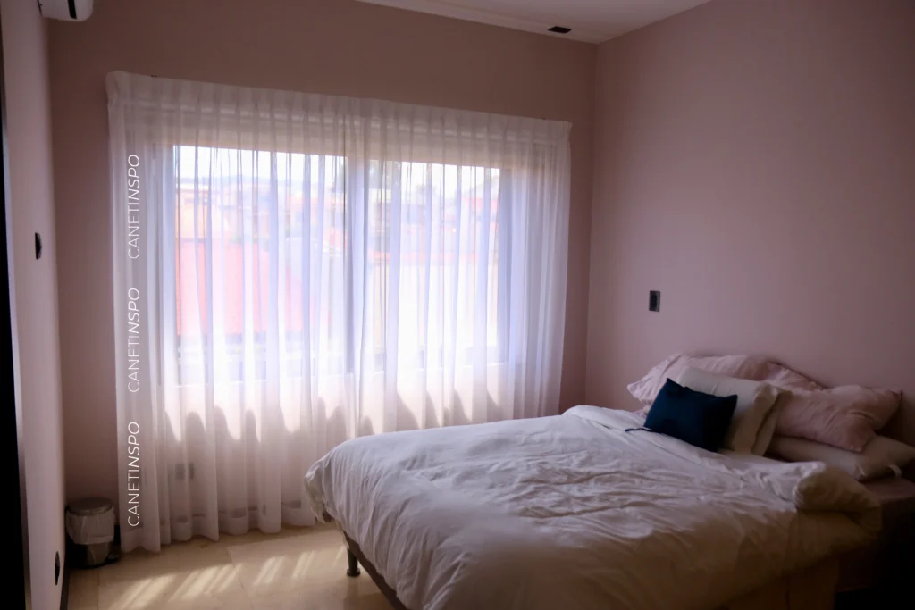 Recámara de alguien que sabe cómo dormir fresco con cortinas en el cuarto que también permiten mejor privacidad
