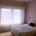 Recámara de alguien que sabe cómo dormir fresco con cortinas en el cuarto que también permiten mejor privacidad