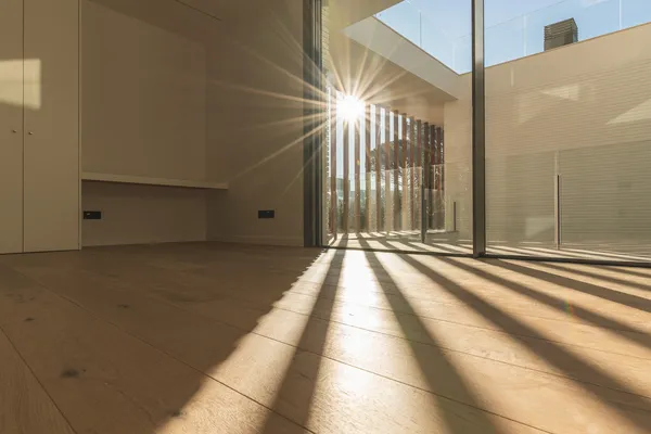Fotografía del interior de un hogar donde hay decoloración en pisos debido a la falta de cortinas en las ventanas